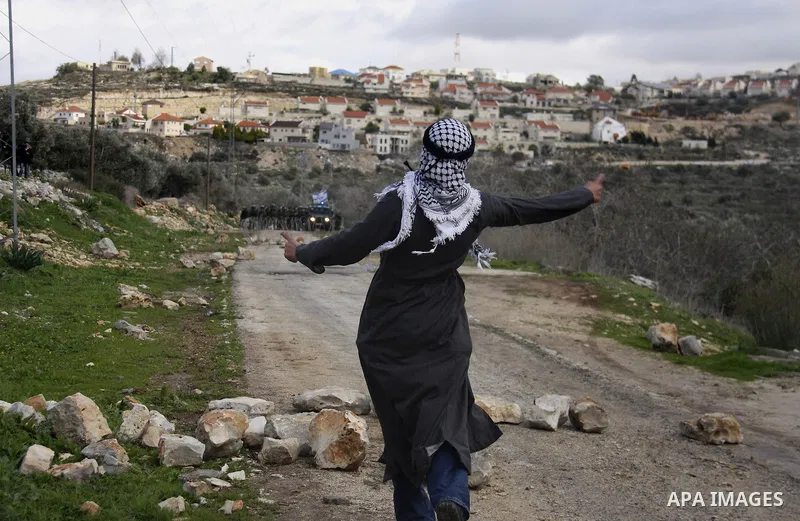 Traditionally dressed Palestinian men hurl stones at Israeli security forces during a protest in the village of Kufr Qaddum near the Israeli settlement of Kdumim, in the northern West Bank, Friday, Jan. 13, 2012. Photo b...