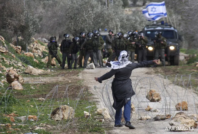 Traditionally dressed Palestinian men hurl stones at Israeli security forces during a protest in the village of Kufr Qaddum near the Israeli settlement of Kdumim, in the northern West Bank, Friday, Jan. 13, 2012. Photo b...