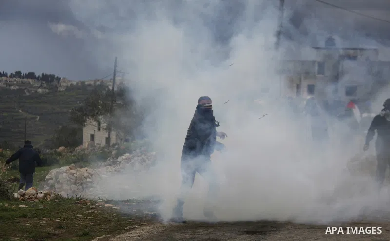 A Palestinian protester throws a tear gas canister back at Israeli troops during a weekly protest against the Jewish settlement of Qadomem, near Nablus, the West Bank, 13 January 2012. Ten Palestinians and two journalist...
