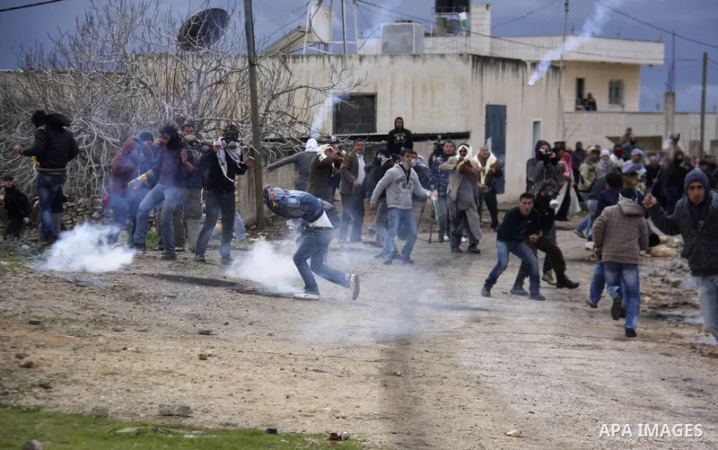 Palestinian protesters clash with Israeli troops as a tear gas canister flies overhead during a weekly protest against the Jewish settlement of Qadomem, near Nablus, the West Bank, 13 January 2012. Ten Palestinians and t...