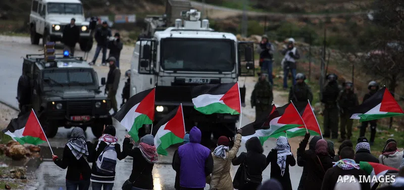 Palestinians wave flags in front of a truck spraying foul smelling water during clashes with stone-throwing demonstrators and Israeli soldiers at a weekly protest in the West Bank village of Nabi Saleh, near Ramallah Jan...
