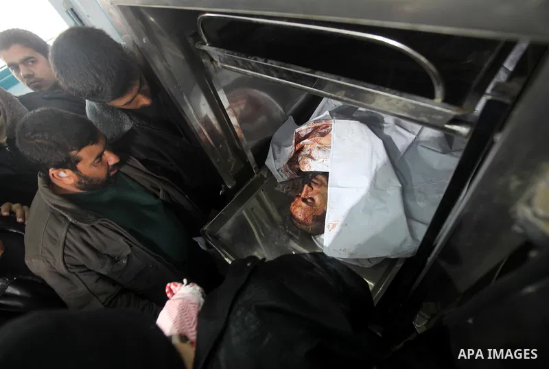Palestinian men look at the body of Mohamed Abu Awda in the morgue, after he was killed in an Israeli airstrike on northern Gaza on January 18, 2012. The raid hit a field used by Hamas in the east of the northern town Be...