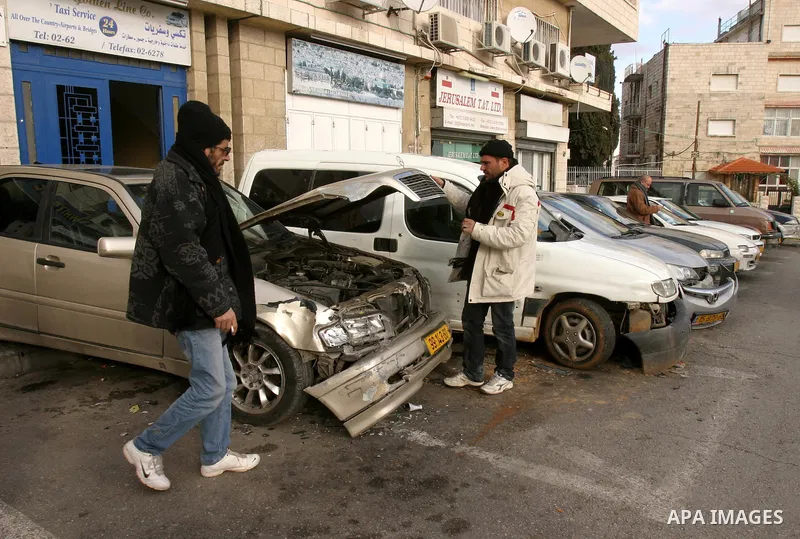 Palestinians inspect damaged cars hit by Israeli police vehicle in East Jerusalem on Jan. 19,2012. Photo by Mahfouz Abu Turk