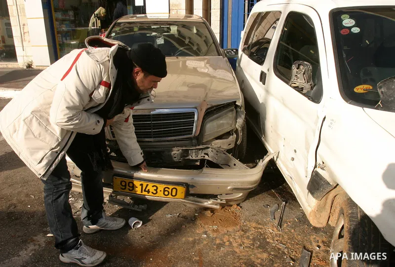 Palestinians inspect damaged cars hit by Israeli police vehicle in East Jerusalem on Jan. 19,2012. Photo by Mahfouz Abu Turk