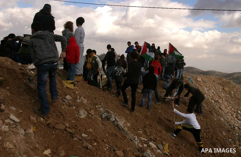 Israeli, Palestinian and foreign activists reopen a blocked road during a protest in the East Jerusalem neighbourhood of Issawiya on January 20, 2012 against a decision by the Jerusalem municipality and Israel's Nature a...
