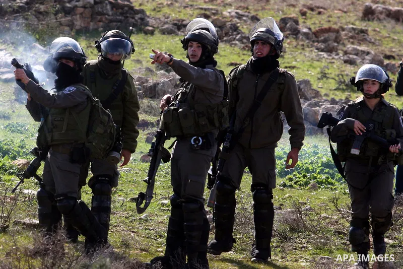 An Israeli border police officer fires a tear gas canister towards stone-throwing Palestinian demonstrators during clashes at a weekly demonstration against the construction and expansion of Israeli settlements in the We...