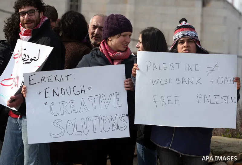 People hold Palestinian flags and placards during a protest against the peace negotiation talks between Palestinians and Israeli in front of Palestinian President Mahmoud Abbas's office in Ramallah, January 21, 2012. The...