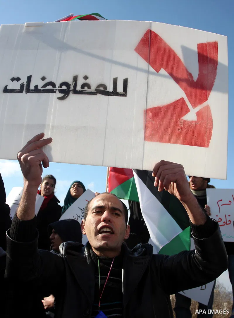 People hold Palestinian flags and placards during a protest against the peace negotiation talks between Palestinians and Israeli in front of Palestinian President Mahmoud Abbas's office in Ramallah, January 21, 2012. The...