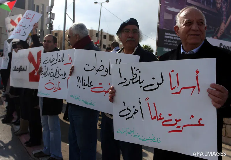 People hold Palestinian flags and placards during a protest against the peace negotiation talks between Palestinians and Israeli in front of Palestinian President Mahmoud Abbas's office in Ramallah, January 21, 2012. The...