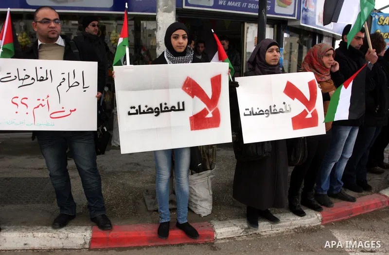 People hold Palestinian flags and placards during a protest against the peace negotiation talks between Palestinians and Israeli in front of Palestinian President Mahmoud Abbas's office in Ramallah, January 21, 2012. The...