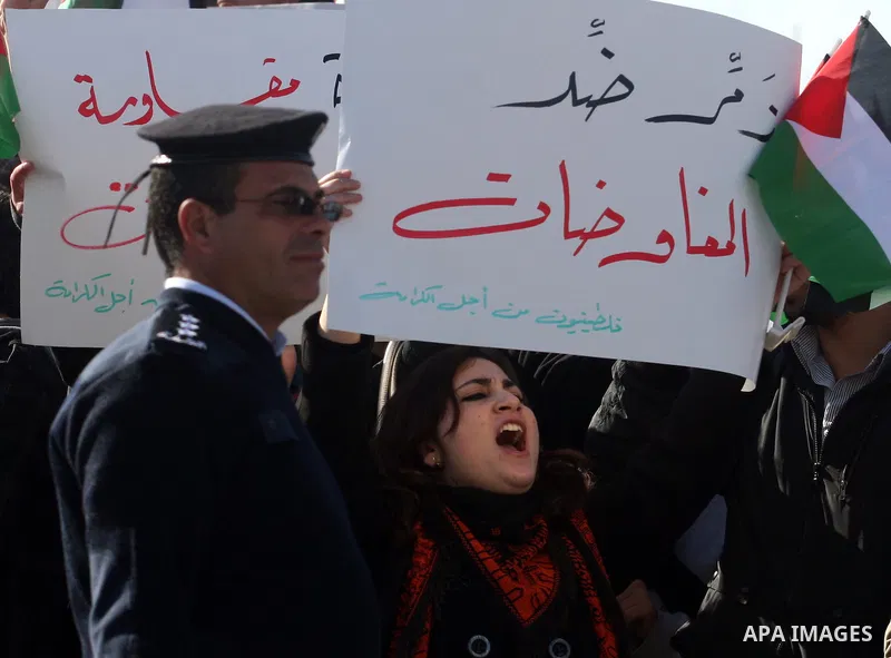 People hold Palestinian flags and placards during a protest against the peace negotiation talks between Palestinians and Israeli in front of Palestinian President Mahmoud Abbas's office in Ramallah, January 21, 2012. The...