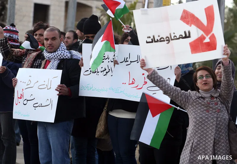 People hold Palestinian flags and placards during a protest against the peace negotiation talks between Palestinians and Israeli in front of Palestinian President Mahmoud Abbas's office in Ramallah, January 21, 2012. The...