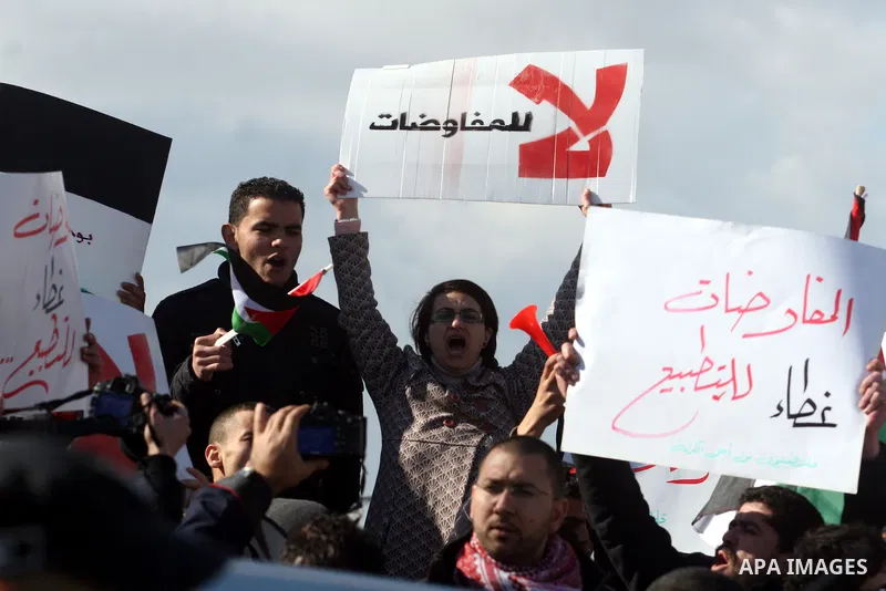 People hold Palestinian flags and placards during a protest against the peace negotiation talks between Palestinians and Israeli in front of Palestinian President Mahmoud Abbas's office in Ramallah, January 21, 2012. The...