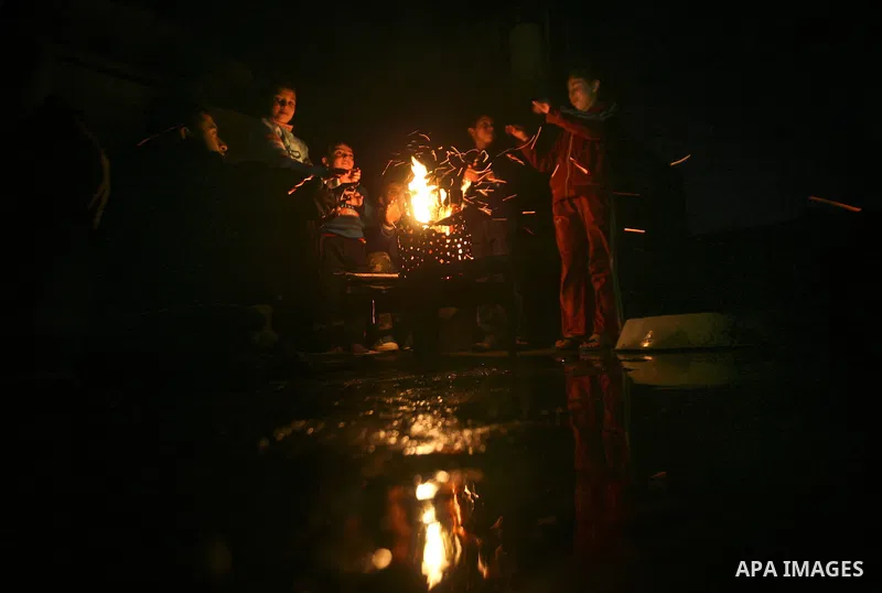 Palestinian people warm up by a fire during a cold winter night in their destroyed house, set up after the Israeli offensive on Gaza two years ago, in Jabaliya refugee camp in northren Gaza Strip on 23 January 2012. Phot...