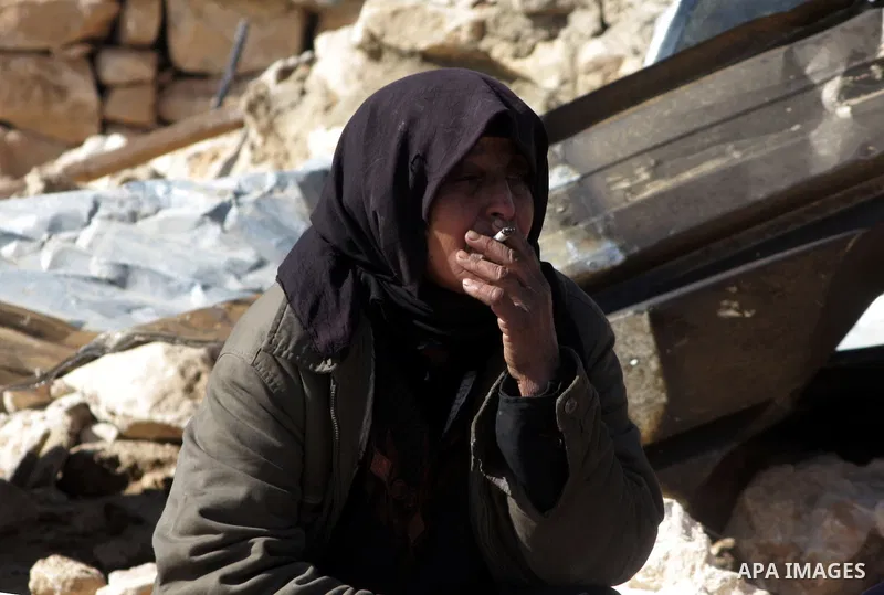 A Palestinian bedouin woman smokes on the rubbles of her destroyed house in Oum al-Khair village southern West Bank city of Hebron after the house was destroyed by the Israeli army on January 25, 2012. Photo by Mamoun Wa...