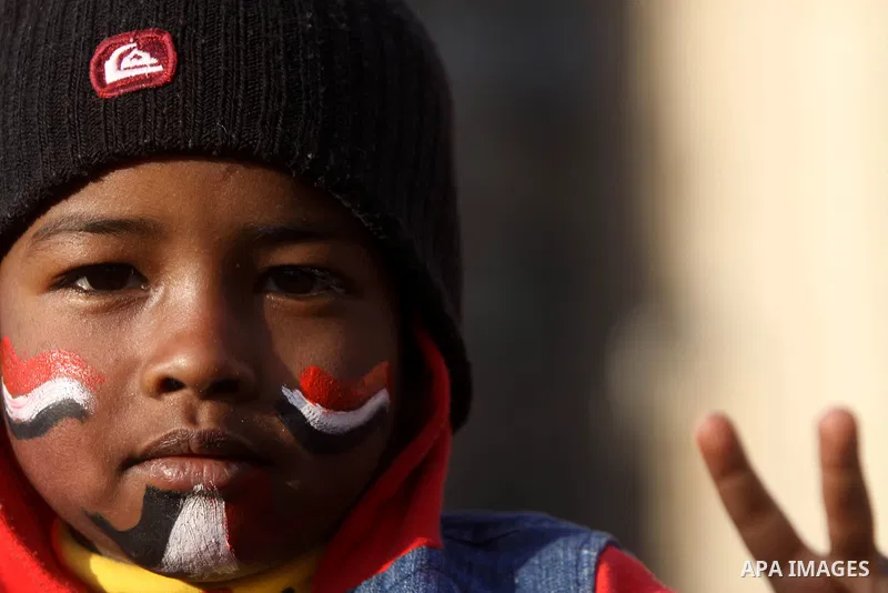 An Egyptian boy paints his face with the national flag during a protest to celebrate the one year anniversary of the 25th January uprising at Tahrir square in Cairo, Egypt, 25 January 2012. One year earlier the same day...