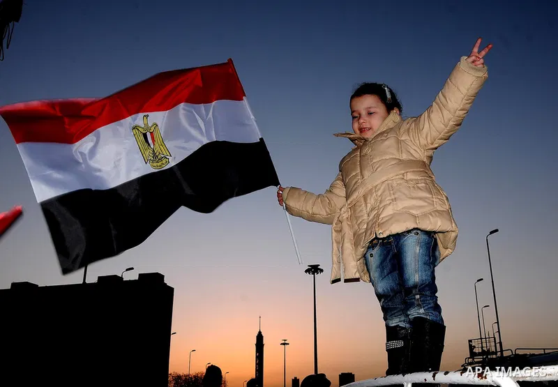 An Egyptian girl waves her national flag at a rally in Tahrir Square to mark the one year anniversary of the uprising that ousted President Hosni Mubarak in Cairo, Egypt, Wednesday, Jan. 25, 2012. Crowds of several hundr...