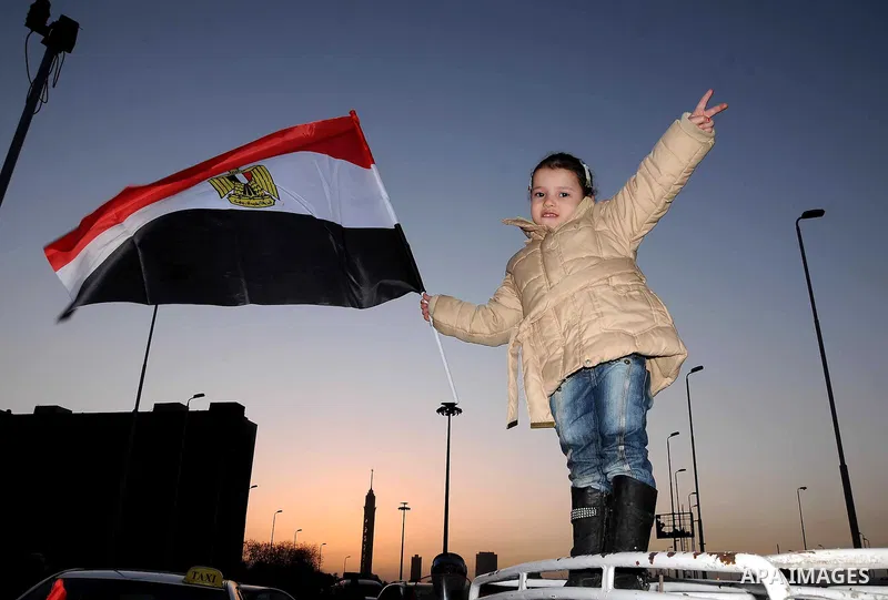 An Egyptian girl waves her national flag at a rally in Tahrir Square to mark the one year anniversary of the uprising that ousted President Hosni Mubarak in Cairo, Egypt, Wednesday, Jan. 25, 2012. Crowds of several hundr...