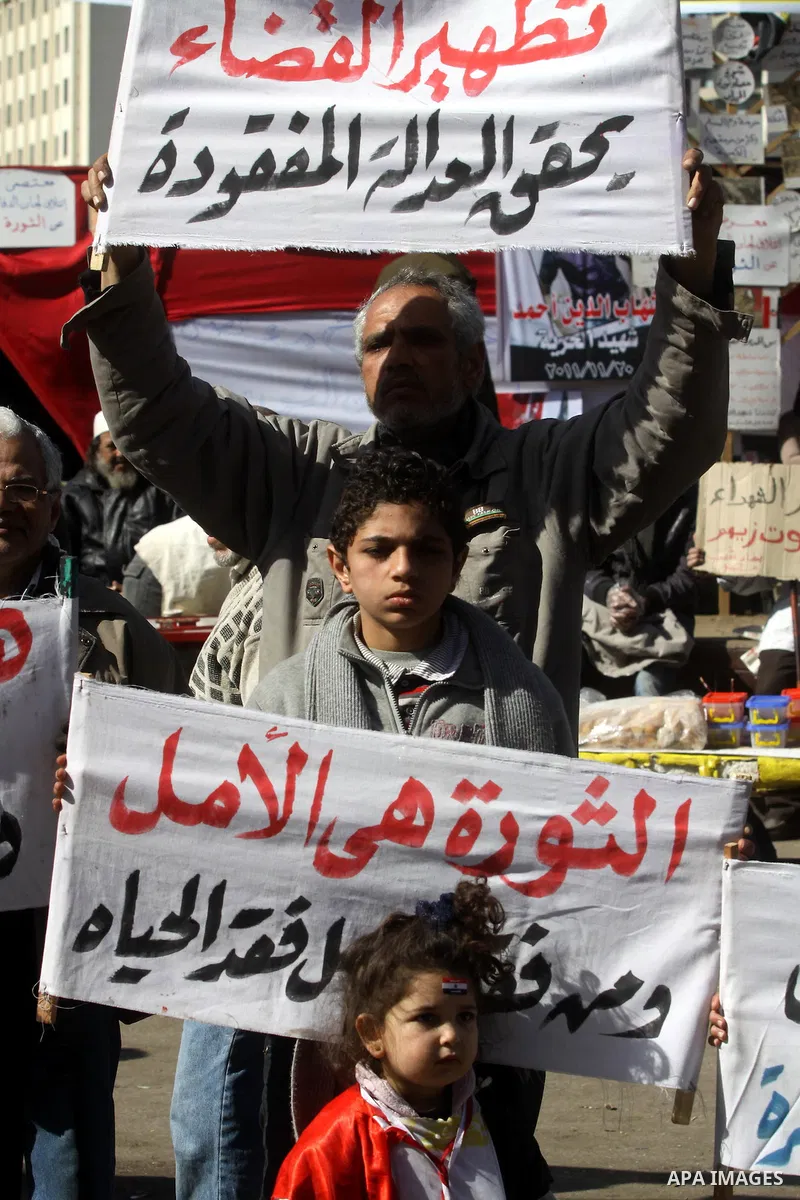 Egyptian demonstrators hold banners during a protest demanding the army to hand power to civilians at Tahrir square in Cairo on January 27, 2012, a year after a popular uprising. The protesters are demanding the implemen...