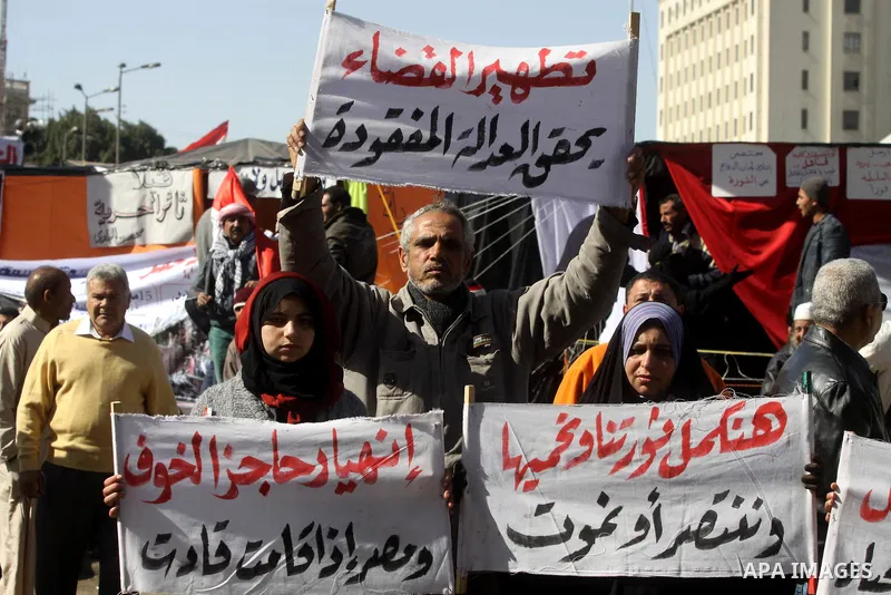 Egyptian demonstrators hold banners during a protest demanding the army to hand power to civilians at Tahrir square in Cairo on January 27, 2012, a year after a popular uprising. The protesters are demanding the implemen...