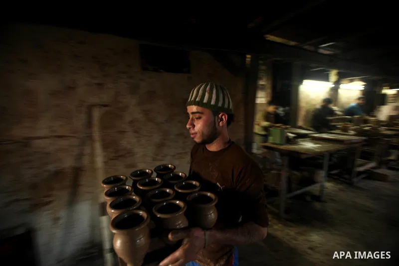 A Palestinian pottery workers spin a pot on a spin wheel at a pottery workshop in Gaza City on Jan 29. 2012. Pottery is a very ancient and traditional industry in Gaza City. Photo by Ashraf Amra. Photo by Ashraf Amra