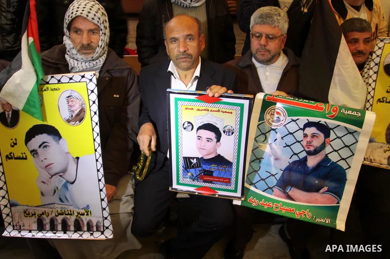 Palestinians hold pictures of their prisoned relatives in Israeli jails as they gather in a weekly activity calling for their liberty at the Red Cross headquarters in Gaza City, on Jan. 30, 2012. Photo by Mohammed Asad