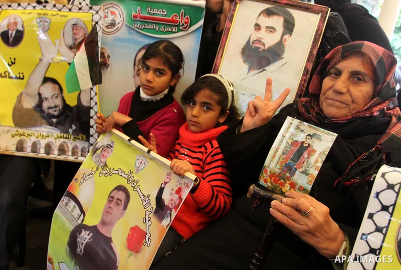 Palestinians hold pictures of their prisoned relatives in Israeli jails as they gather in a weekly activity calling for their liberty at the Red Cross headquarters in Gaza City, on Jan. 30, 2012. Photo by Mohammed Asad