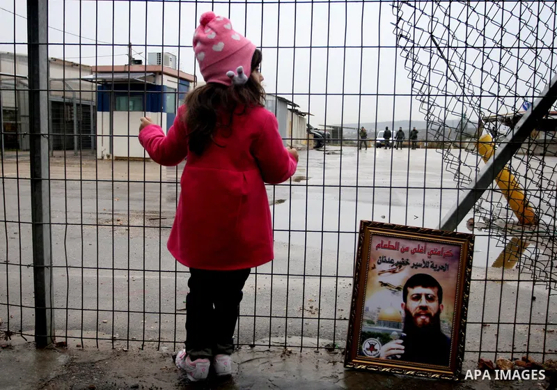Maali, daughter of jailed Islamic Jihad spokesman Khodr Adnan, stands next to a picture of her father as she takes part in a protest outside Israel's Ofer prison near the West Bank town of Betunia on January 30, 2012. Ad...