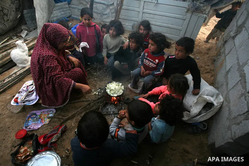A Palestinian woman, from a Bedouin family, sits with her children preparing food during low winter temperatures inside her family's tent in Gaza's Zeitoun neighbourhood January 31, 2012. Photo by Mahmud Nassar