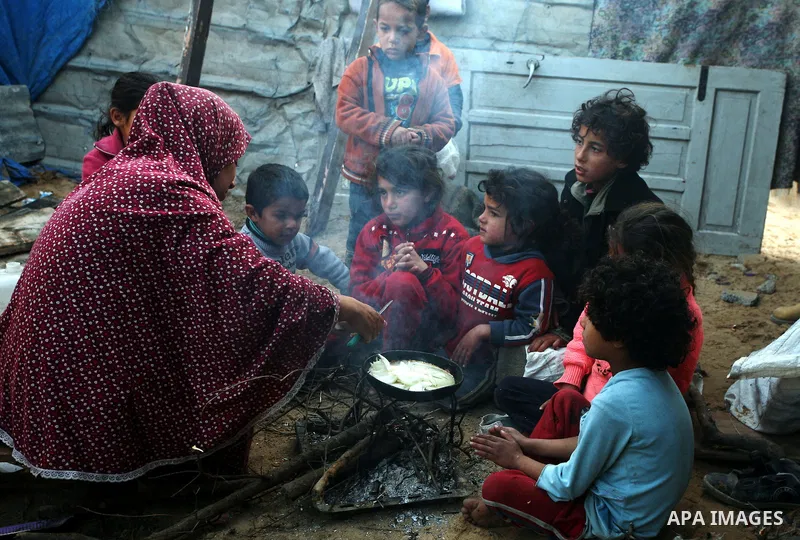 A Palestinian woman, from a Bedouin family, sits with her children preparing food during low winter temperatures inside her family's tent in Gaza's Zeitoun neighbourhood January 31, 2012. Photo by Mahmud Nassar