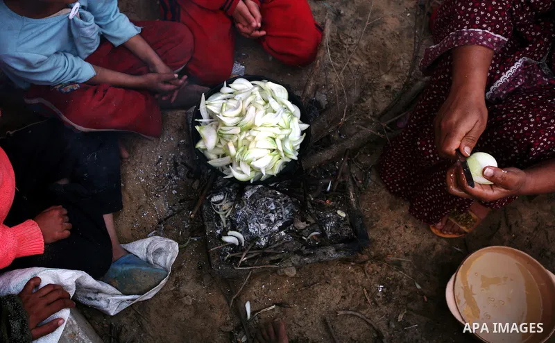 A Palestinian woman, from a Bedouin family, sits with her children preparing food during low winter temperatures inside her family's tent in Gaza's Zeitoun neighbourhood January 31, 2012. Photo by Mahmud Nassar