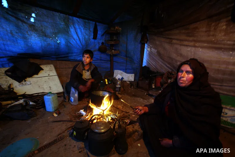 A Palestinian woman, from a Bedouin family, sits with her children preparing food during low winter temperatures inside her family's tent in Gaza's Zeitoun neighbourhood January 31, 2012. Photo by Mahmud Nassar