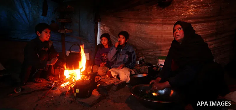 A Palestinian woman, from a Bedouin family, sits with her children preparing food during low winter temperatures inside her family's tent in Gaza's Zeitoun neighbourhood January 31, 2012. Photo by Mahmud Nassar