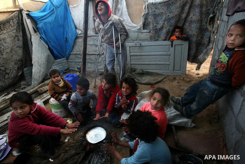 A Palestinian woman, from a Bedouin family, sits with her children preparing food during low winter temperatures inside her family's tent in Gaza's Zeitoun neighbourhood January 31, 2012. Photo by Mahmud Nassar