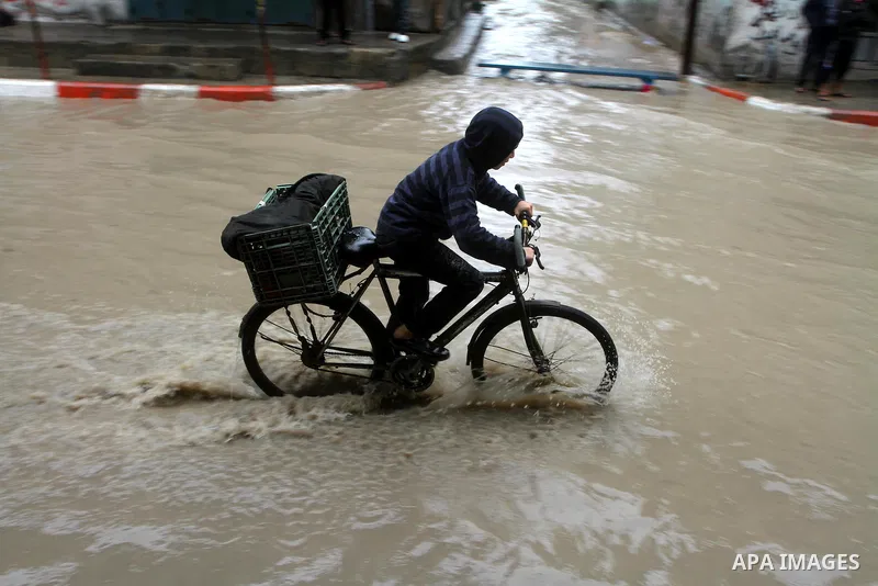 Palestinians walk in a street during the heavy rain of the winter, in the Gaza City, Feb. 01, 2012. Photo by Ashraf Amra