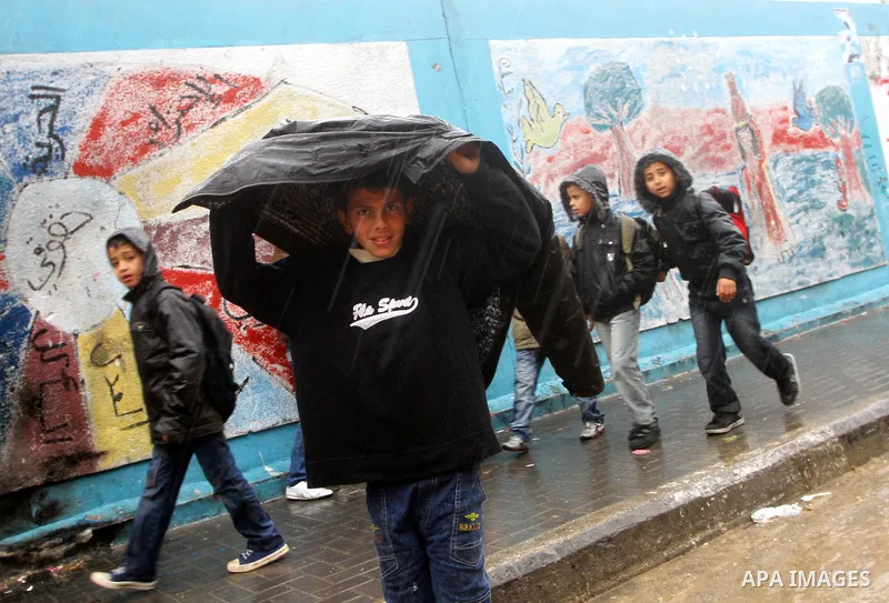 Palestinian students stand in a street during the heavy rain of the winter, in the Gaza City, Feb. 01, 2012. Photo by Ashraf Amra