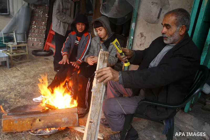 Palestinian people warm up by a fire during the heavy rain of the winter, in the Gaza City, Feb. 01, 2012. Photo by Ashraf Amra