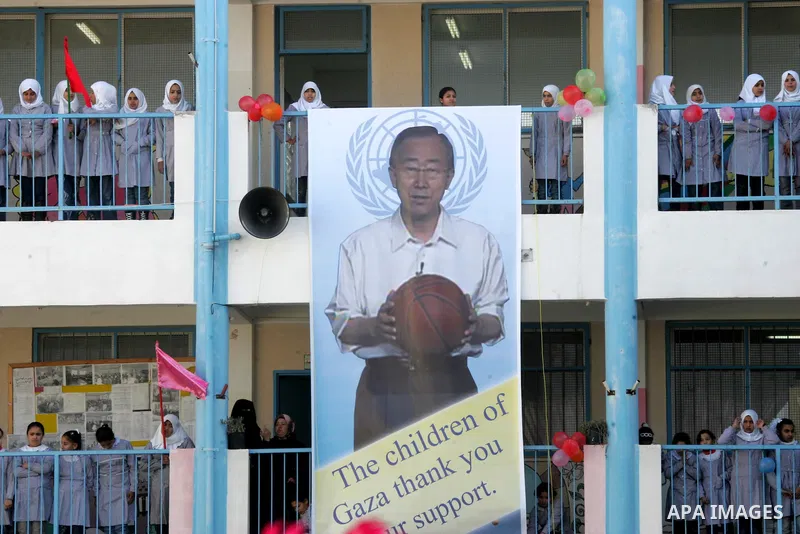 Palestinian schoolgirls stand next a poster for UN secretary general Ban Ki-moon during his visit to their school in Khan Yunis in the southern Gaza Strip on February 2, 2012. Protesters threw shoes, sand and small stone...