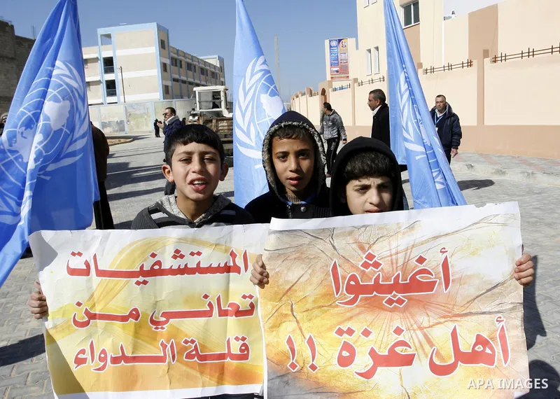 Palestinian children hold slogans during a visit by UN secretary general Ban Ki-moon to the construction site of a housing project in Khan Yunis in the southern Gaza Strip on February 2, 2012. Protesters threw shoes, san...