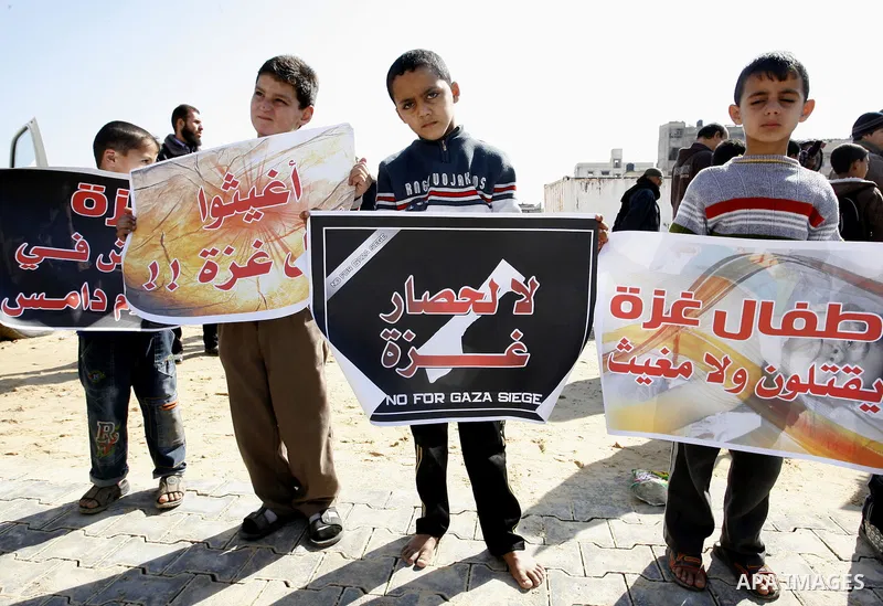 Palestinian children hold slogans during a visit by UN secretary general Ban Ki-moon to the construction site of a housing project in Khan Yunis in the southern Gaza Strip on February 2, 2012. Protesters threw shoes, san...