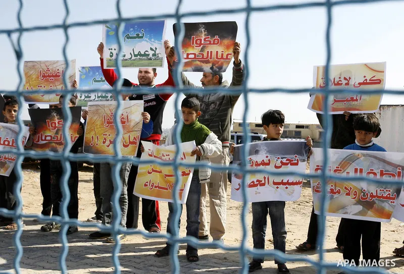 Palestinian children hold slogans during a visit by UN secretary general Ban Ki-moon to the construction site of a housing project in Khan Yunis in the southern Gaza Strip on February 2, 2012. Protesters threw shoes, san...