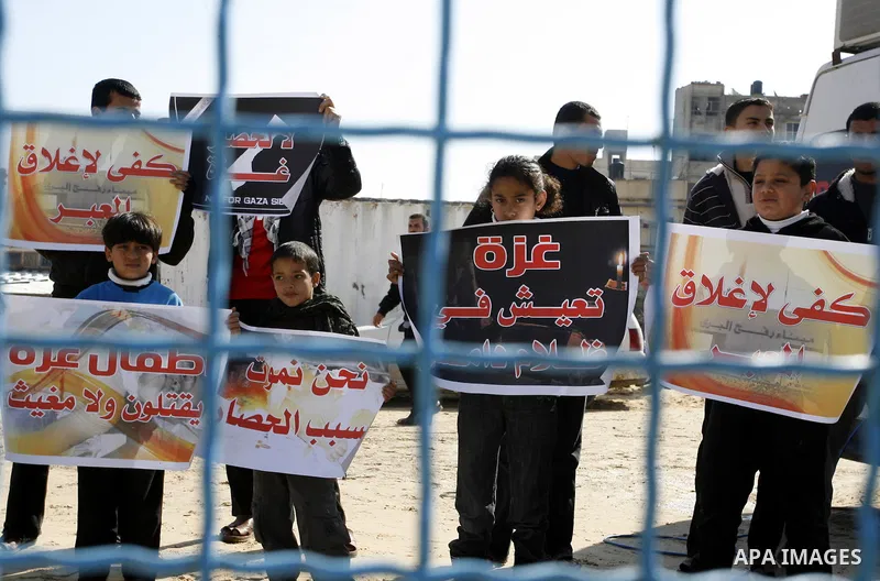 Palestinian children hold slogans during a visit by UN secretary general Ban Ki-moon to the construction site of a housing project in Khan Yunis in the southern Gaza Strip on February 2, 2012. Protesters threw shoes, san...