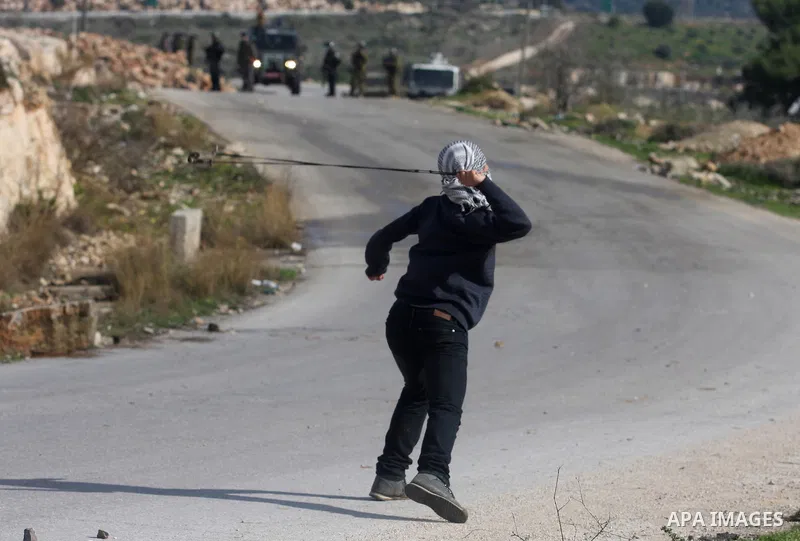 A Palestinian youth hurls stones at Israeli troops during a weekly protest against the construction of Israel's controversial separation barrier and the expansion of Jewish settlements in the West Bank village of Nabi Sa...