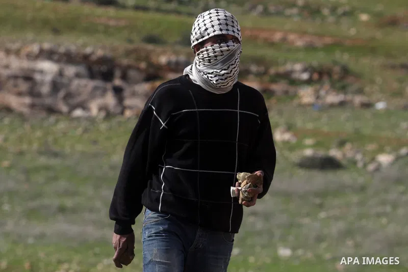 A Palestinian youth hurls stones at Israeli troops during a weekly protest against the construction of Israel's controversial separation barrier and the expansion of Jewish settlements in the West Bank village of Nabi Sa...