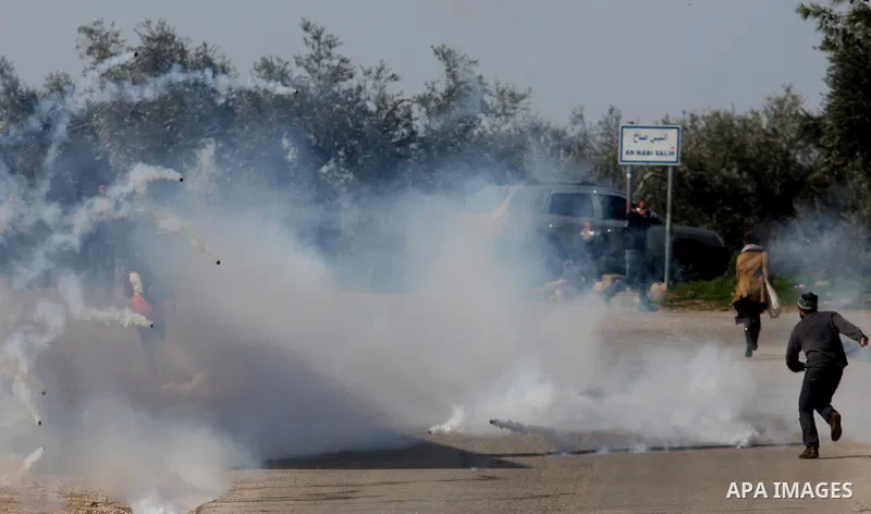 A Palestinian demonstrator runs for cover as Israeli soldiers fire tear gas during a weekly protest against the construction of Israel's controversial separation barrier and the expansion of Jewish settlements in the Wes...