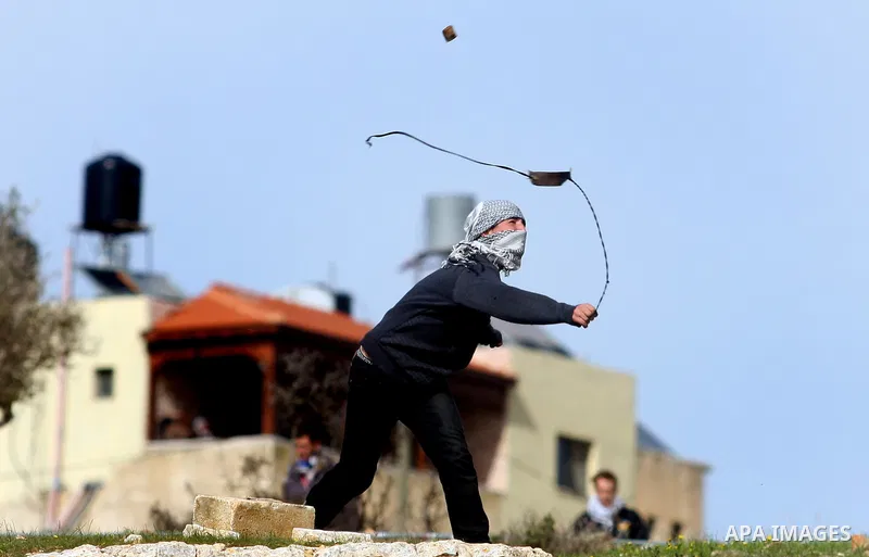 A Palestinian youth hurls stones at Israeli troops during a weekly protest against the construction of Israel's controversial separation barrier and the expansion of Jewish settlements in the West Bank village of Nabi Sa...