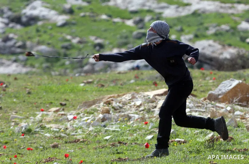 A Palestinian youth hurls stones at Israeli troops during a weekly protest against the construction of Israel's controversial separation barrier and the expansion of Jewish settlements in the West Bank village of Nabi Sa...