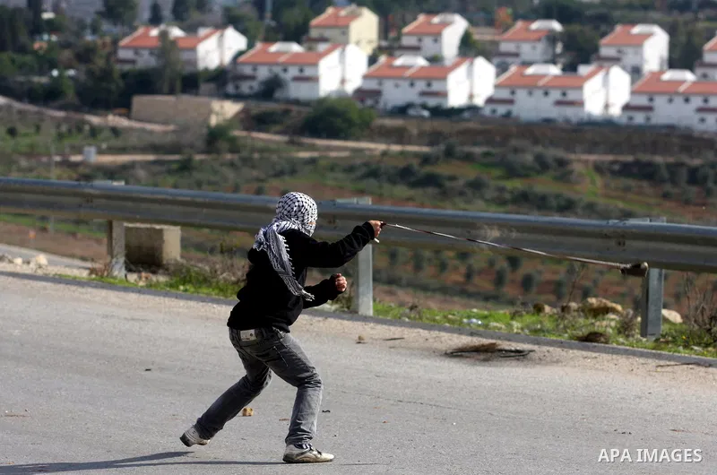 A Palestinian youth hurls stones at Israeli troops during a weekly protest against the construction of Israel's controversial separation barrier and the expansion of Jewish settlements in the West Bank village of Nabi Sa...