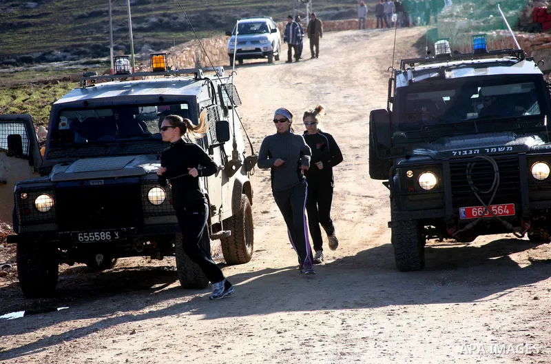 Israeli soldiers block the road in front of Palestinians, Israeli and foreign activists during a marathon to support the farmers and land owners in the West Bank city of Hebron on Feb. 4,2012. Israeli troops detained a P...
