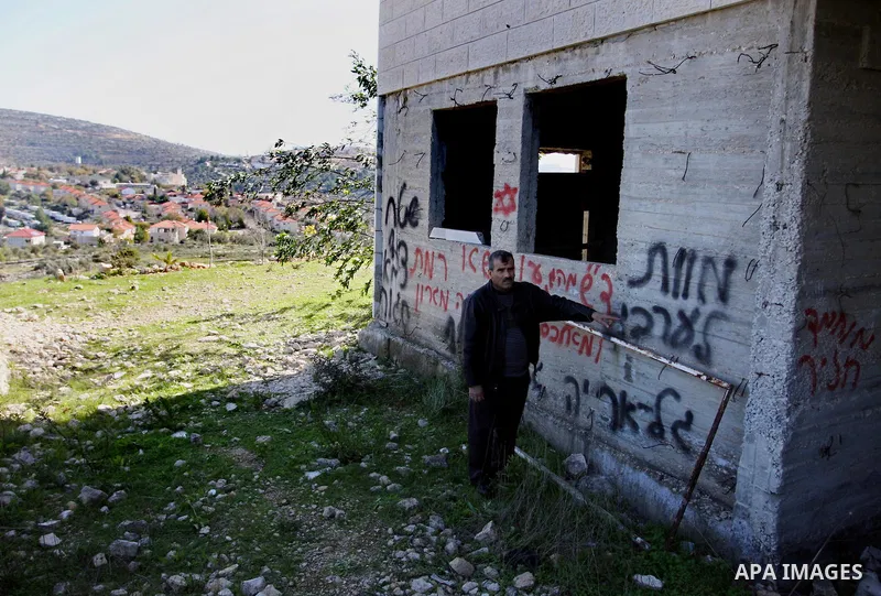 Palestinians look at graffiti sprayed on his house in the West Bank village of El-Jinya near Ramallah, Sunday, Feb. 5, 2012. Palestinians say extremist Jews have scrawled their home in a West Bank village with offensive...